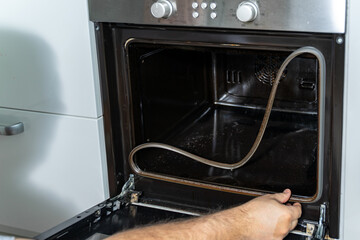 the man removes the rubber bands from the oven. repair and cleaning of an electric oven