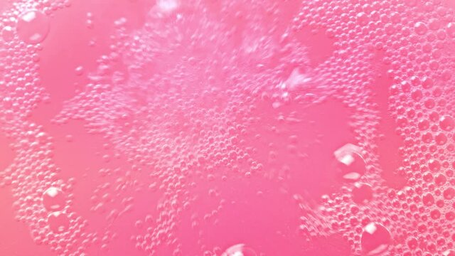 Pink bubbling liquid boiling texture. Carbonated drink background.