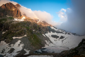 Beautiful alpine second lake Klukhor, under a layer of ice and snow on the border of Russia and Abkhazia