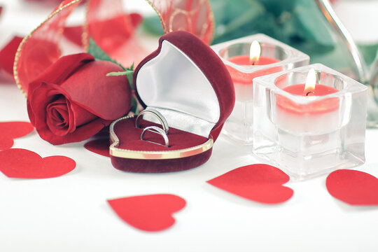 wedding rings, candles and rose on white background