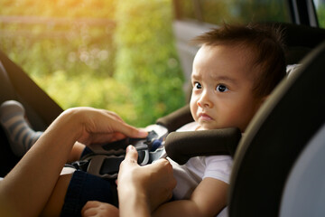 Asian little baby sad while fastened belt and seat in the safety car seat. A boy looking his mother...