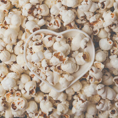 Some homemade Popcorn as detailed close-up shot, heart shaped bowl, top view. Instagram matte filter.