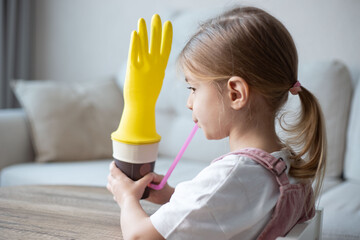 Little girl make an exercise for articulation speech at home. Fun and easy. Preschooler blowing a glove game for speech and articulation.