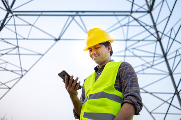 Electrical engineers asian using smartphone inspect the high voltage pole