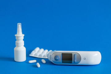 FFP3 mask, nasal drops, thermometer, tablets, various medicines lie on the table, top view, on a blue background