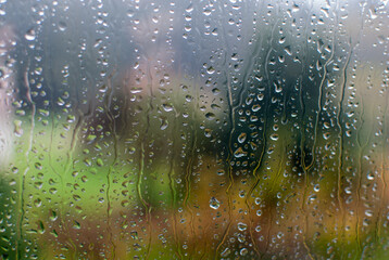 gotas de lluvia sobre cristal de ventana. Vista desde el interior del hogar en un día triste y...