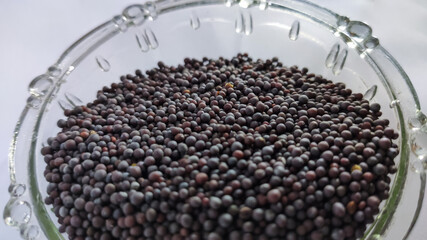 mustard seeds in glass bowl on a white isolated surface