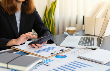 Close-up business women using a calculator and a laptop to calculate the company's financial results On the wooden table in the office and business work background, tax, accounting, statistics and ana