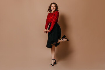 Good-looking woman funny dancing on brown background. Enchanting lady in red sweater posing in studio.