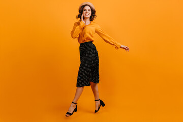 Jocund girl in straw hat jumping on yellow background. Studio shot of blithesome woman dancing with smile.