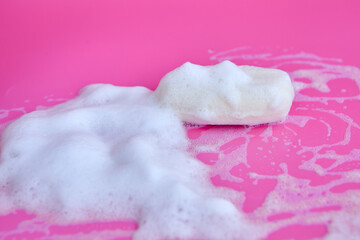 Washing concept. Foam bubbles and brick of soap on pink background. Cleaning service