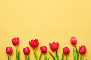 Greeting card. Border of red tulips on a yellow background. Top view, copy space