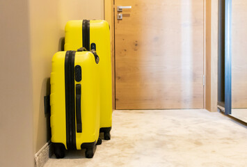 Two yellow travel bags in hotel room.