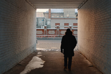 A silhouette of a man in black outfit walking in alleyway