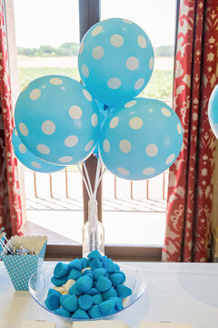 Globos azules con puntitos blancos sobre unos caramelos de az&uacute;car del mismo color. Imagen vertical de una decoraci&oacute;n de fiesta.
