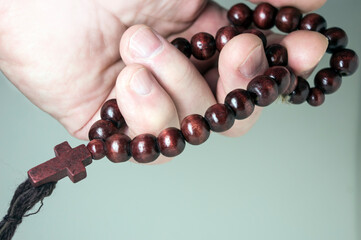 a man's hand holds a rosary