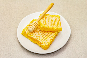 Honeycomb and wooden honey dipper as beekeeping products for a healthy and beauty lifestyle