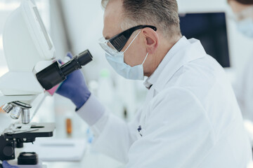 close up. microbiologist a scientist looking through a microscope.