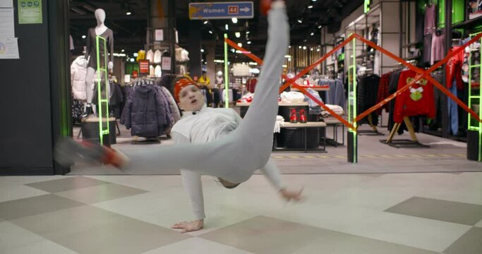 Young cool man break dancer performing in modern shopping mall