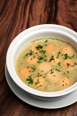 German traditional KARTOFFELSUPPE potato and sausage soup on wood table