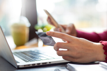 Close up woman hand using credit card and smartphone laptop for buying online shopping