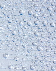 Water drops on blue glass as an abstract background.
