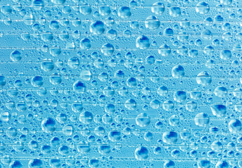 Water drops on blue glass as an abstract background.