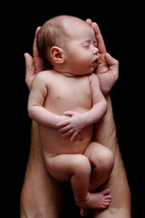 Cute newborn baby lying in the father's hands