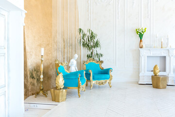 Luxury light interior of living room with gold wall and chic expensive furniture in white and gold colors