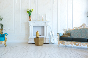 Luxury light interior of living room with gold wall and chic expensive furniture in white and gold colors