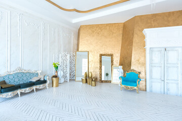 Luxury light interior of living room with gold wall and chic expensive furniture in white and gold colors