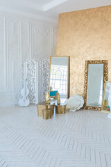 Luxury light interior of living room with gold wall and chic expensive furniture in white and gold colors