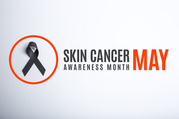 Skin cancer awareness month. May. Black handmade awareness paper ribbon on white background.