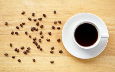 Flat lay view of dark hot coffee cup and coffee beans on wood desk with copy space 