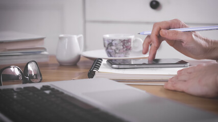 working at home, smart working. woman is set down and uses smartphone and laptop on desk. Girl uses