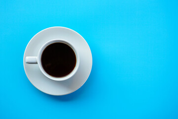 Flat lay view of dark hot coffee cup on blue background with copy space 