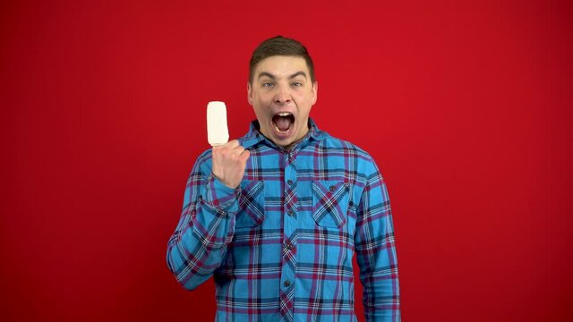 The young man's index finger is bandaged and sore. Shooting on a red background.