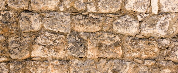 Natural old beige stone wall textured banner. Close up. Copy space.	