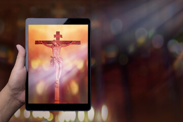 hand hold tablet screen with jesus on the cross, worship from home streaming of church service