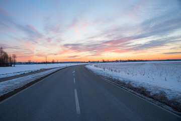 country road with curve in winter landscape, dreamy sunset sky, Brunnthal village, upper bavaria
