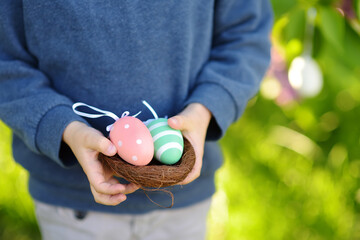 Little boy hunting for eggs in spring park on Easter day. Traditional entertainment during easter...
