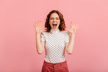 Stressed girl in t-shirt yelling. Studio shot of screaming woman isolated on pink background.