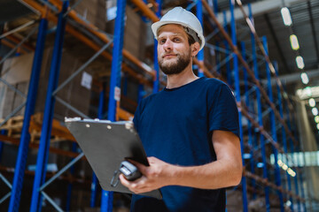 young warehouse manager checking goods using a clipboard in a warehouse