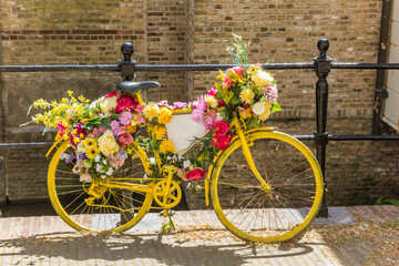 Fototapeta na wymiar Yellow bicycle decorated with flowers at the canal in Gouda, Netherlands