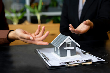The real estate agent is explaining the home model and the details of the contract with the buyer,...