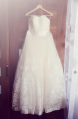 Fototapeta na wymiar The bride's white wedding dress hangs on the wardrobe
