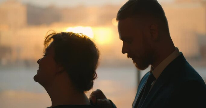 Side view of man slowly unzipping dress from behind unveiling bare female shoulders