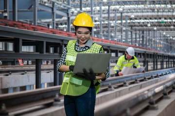 Portrait industry women worker using laptop with man worker working on background. 
