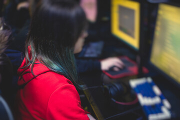 Female gamer, cyber sport e-sports tournament, professional girl gamers, close-up on gamer's hands on a keyboard, pushing button,  in a cyber games arena club, girls playing and streaming fps game