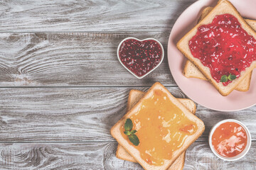 Delicious toasts with various sweet jams on grey background. Copyspace for your text, banner.
